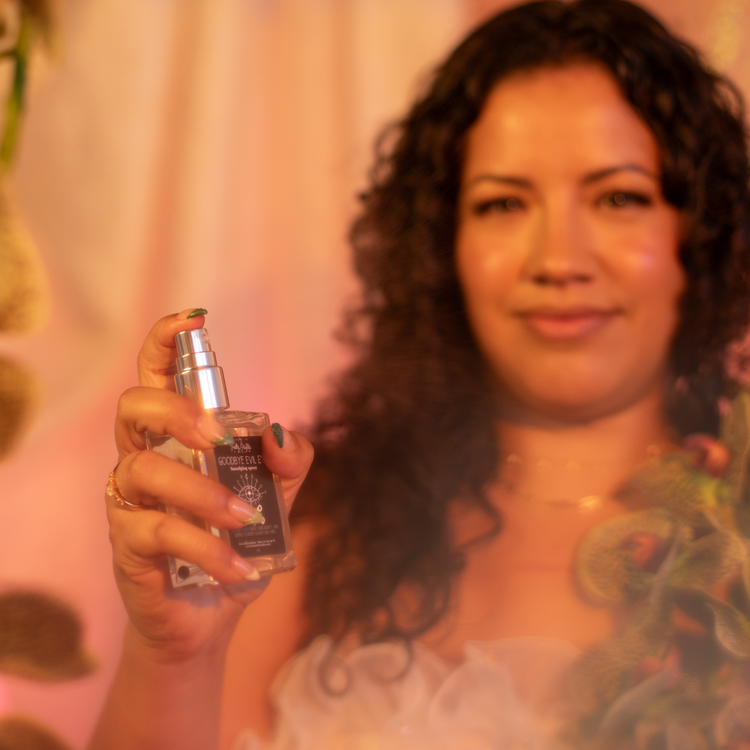 A woman with curly gaur hods a clear square glass bottle with a black label and silver cap