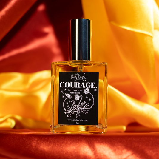 a bottle of perfume with a silver cap and black label with white writing is sitting on top of a red and yellow cloth