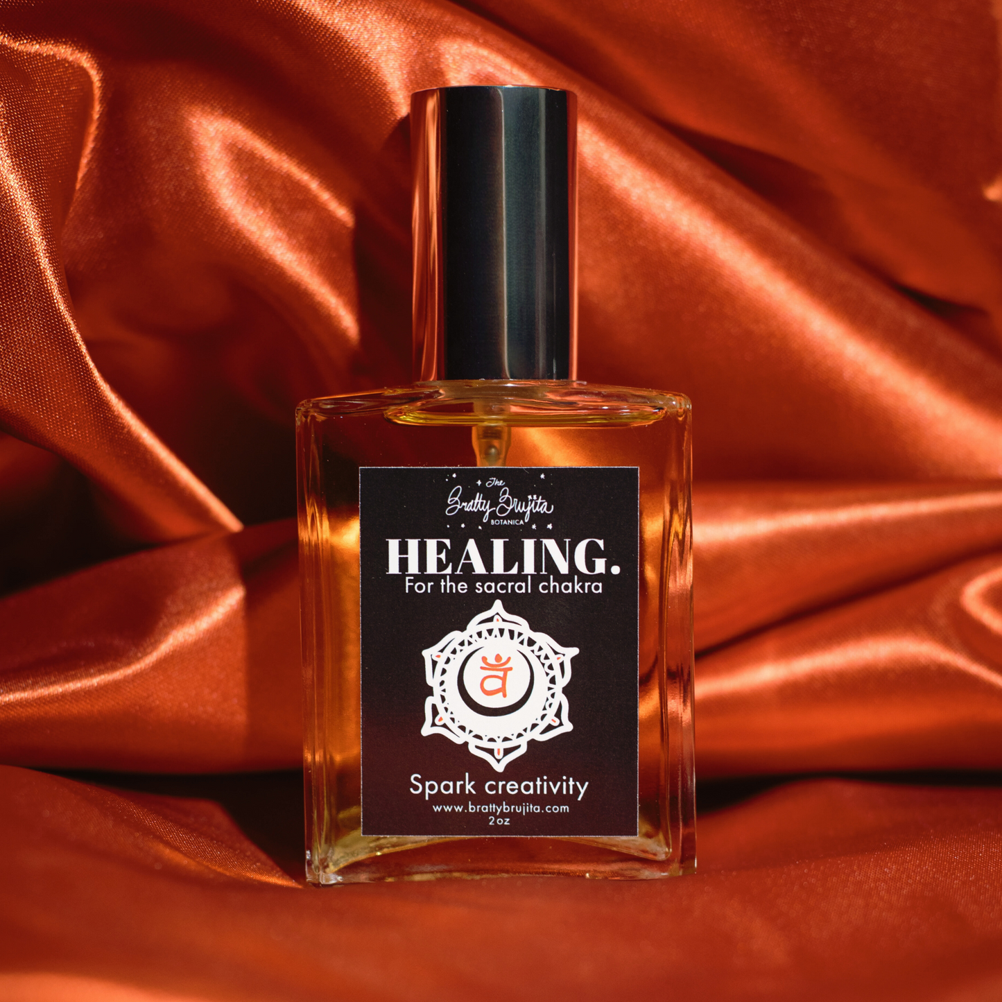 An orange back drop with a square glass bottle with a silver cap and black label and white writing