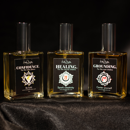 A black background with three square glass bottles with silver caps and black labels with white writing