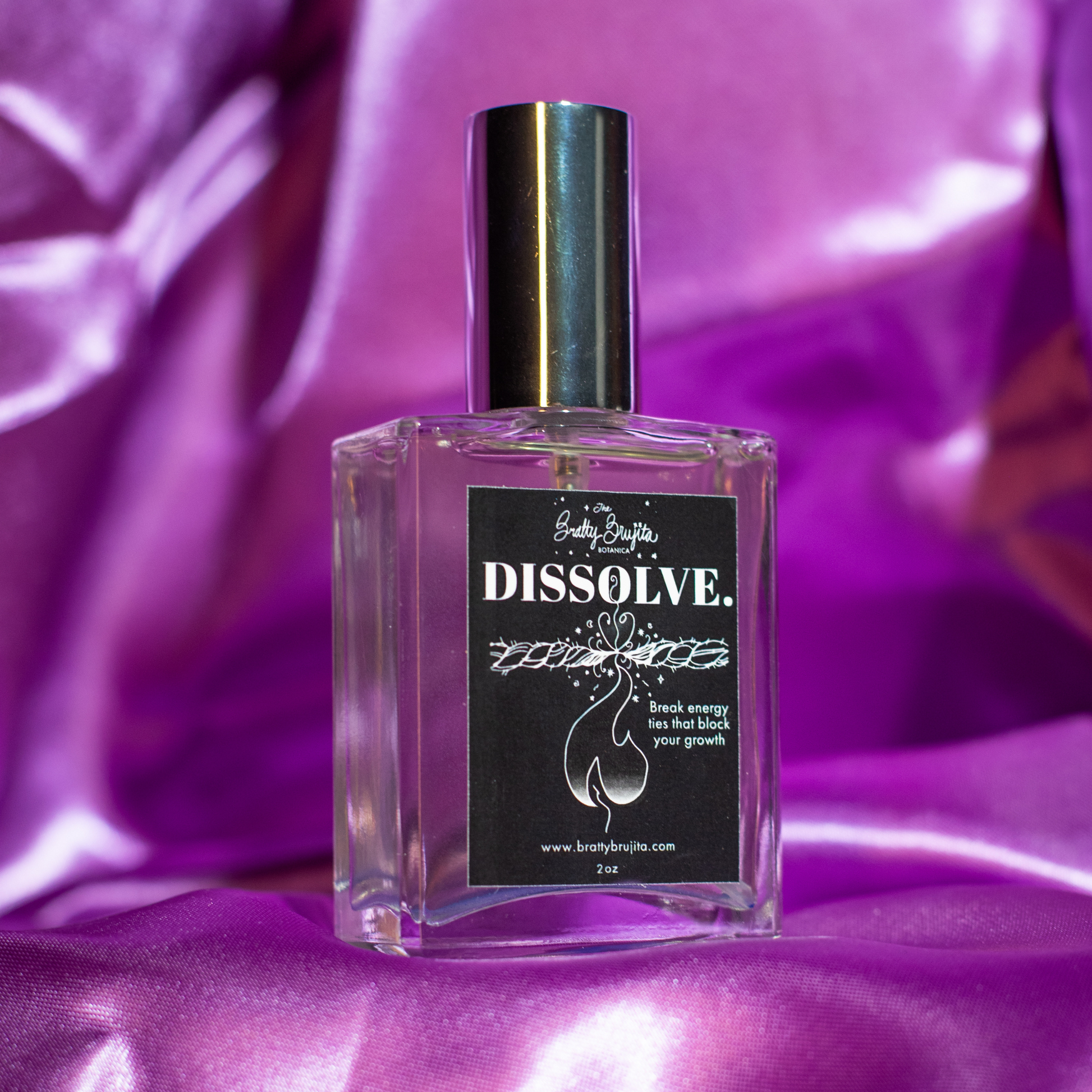 A square glass bottle with a silver cap and black label with white lettering and a flame burning a rope under the word dissolve